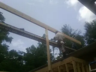 Carpenter setting a ridge beam over a new addition frame — Ice Dam Removal by Roofing Brothers in Hillister