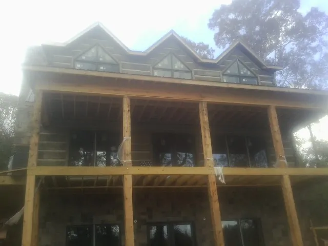 Dormers and porch framing on a large log home under construction in Hillister