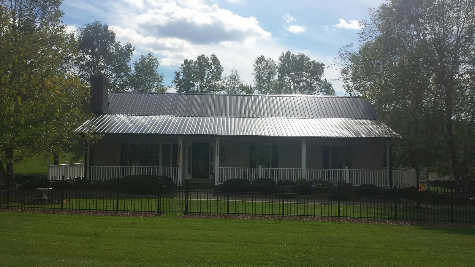 Gray metal roof on a brick ranch with a full width front porch — Gutter Guard Installation work by our crew in Hillister