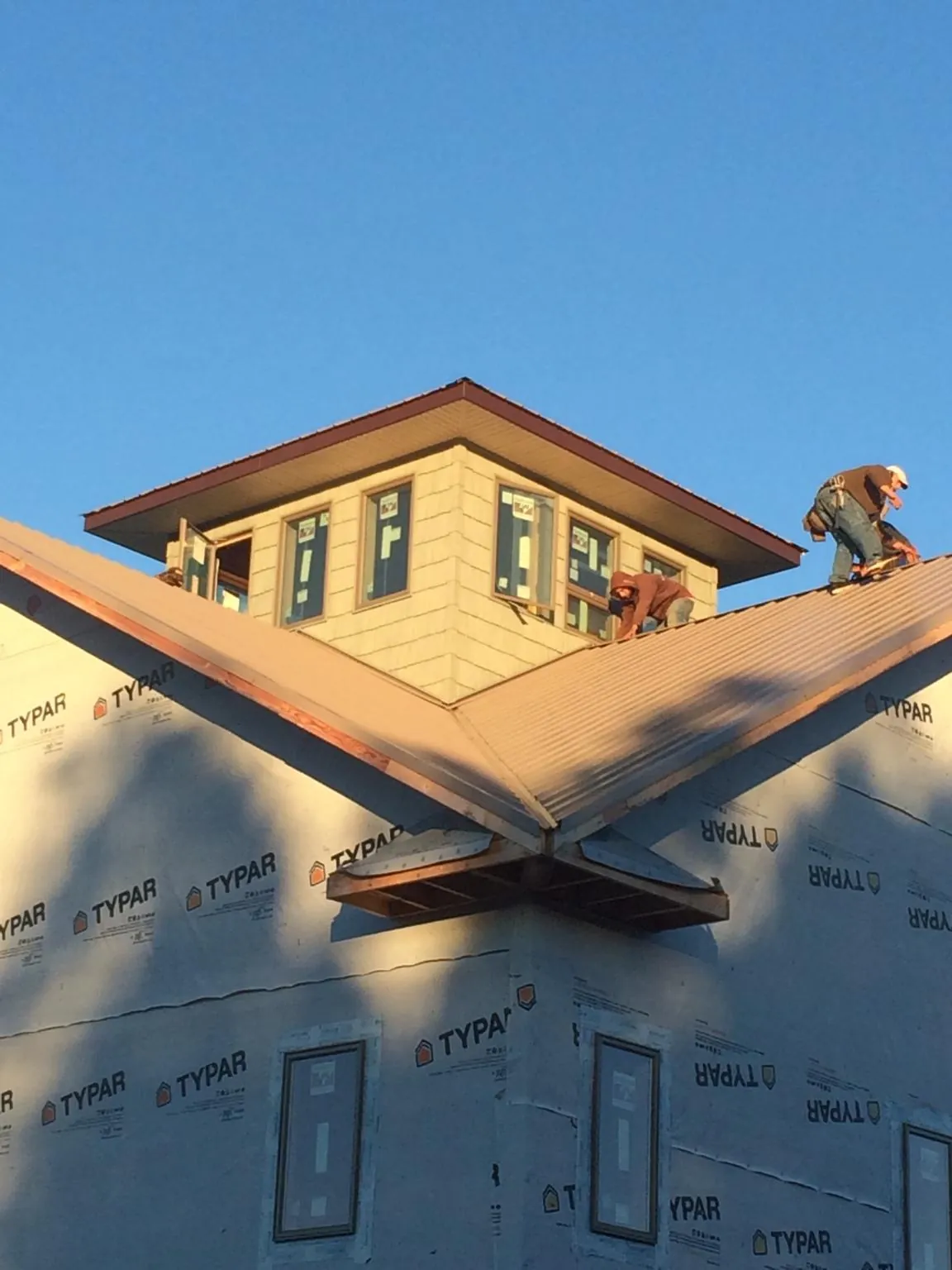 Roofers working around a rooftop cupola on a new metal roof at sunset — Roof Waterproofing in Hillister by Roofing Brothers